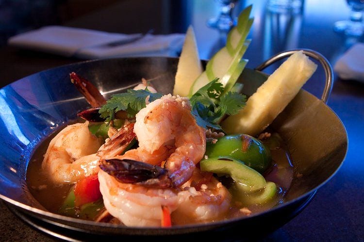 Grilled shrimp dish with pineapple, lime and herbs in a metal bowl